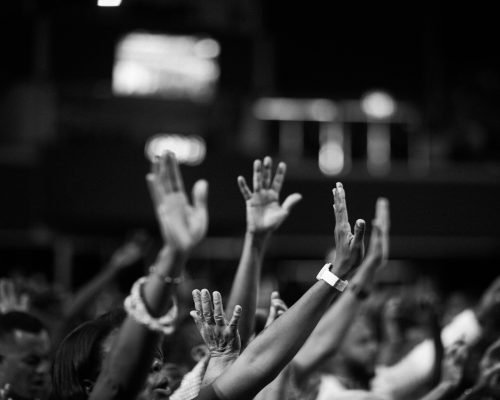 Grayscale Photography of People Raising Hands