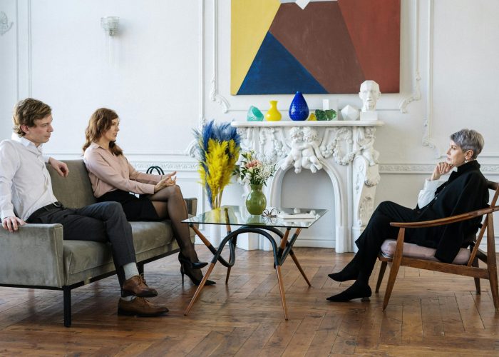 A couple engages in a therapy session with a professional counselor in a stylish interior setting.