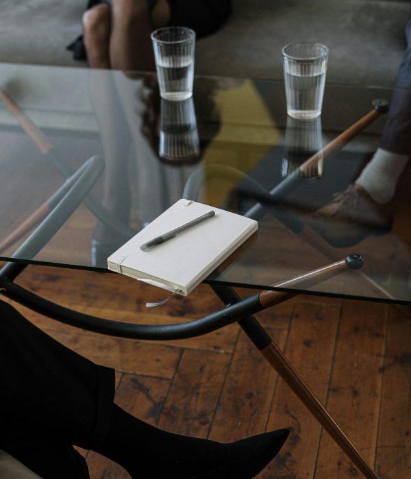 Close-up of a counseling session with two glasses of water and a notepad on a glass table.