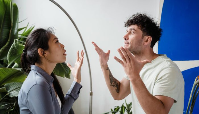 A couple argues indoors amidst greenery, showcasing emotions and interpersonal conflict.
